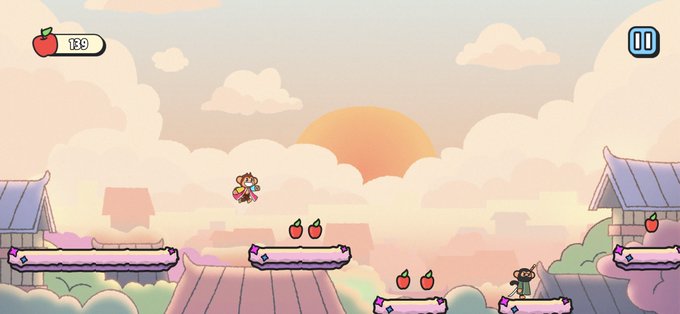 A colorful 2D platformer video game screenshot showing a character collecting red apples against a sunset sky with Japanese-style rooftops.