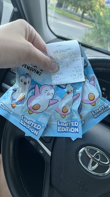 A hand holding a receipt and several limited edition Pokémon Penguins snack packets inside a Toyota vehicle, with the packages featuring illustrations of Piplup penguins.