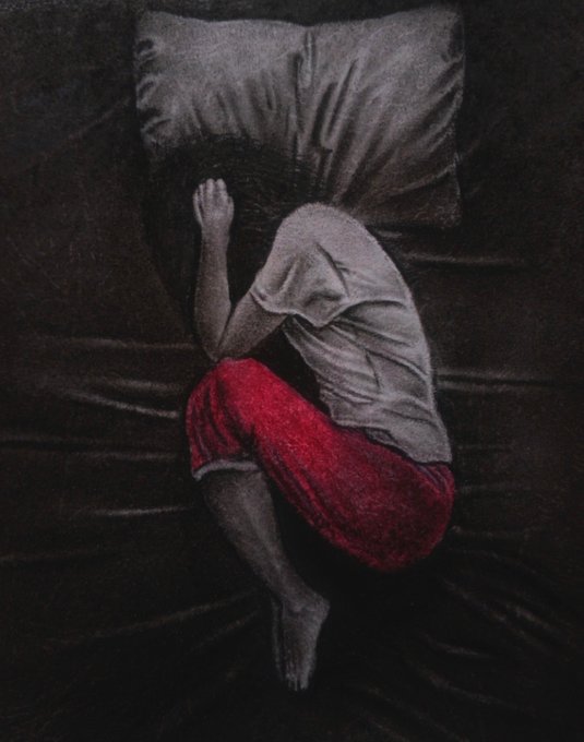 An illustration depicts a person curled up on a dark bed, face hidden, wearing a gray shirt and red shorts, conveying a sense of isolation or sadness.
