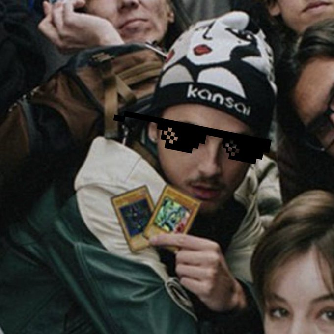 A crowded concert-goer wearing a "kansai" beanie holds up two trading cards (appearing to be Yu-Gi-Oh! cards) while pixelated sunglasses have been edited over his eyes. The post connects to the meme's theme by humorously framing the moment as the "pitch" exchanges have been waiting for.