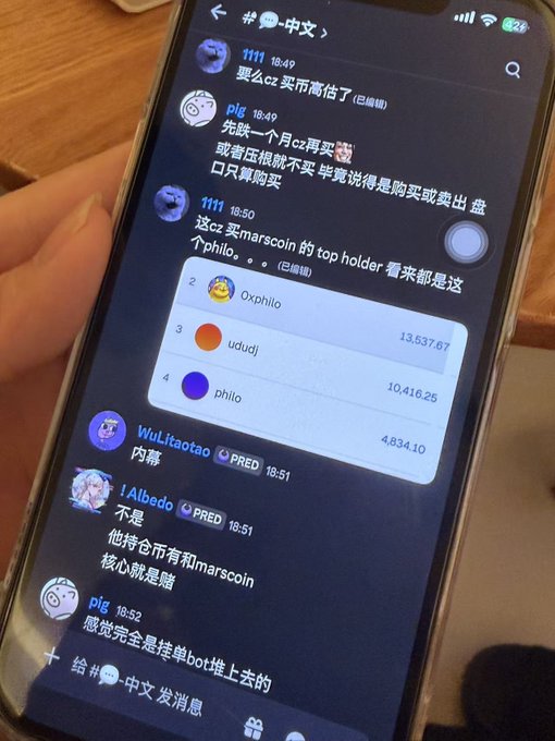 A hand holds a smartphone displaying a Chinese-language Telegram chat where users discuss crypto holdings, showing a ranking of top $marscoin holders: "Oxphilo" (13,537.67), "ududj" (10,416.25), and "philo" (4,834.10). The conversation mentions CZ potentially buying $marscoin and includes comments like "这cz买marscoin的top holder看来都是这个philo" (CZ's top holder for marscoin seems to be this philo) and "他持仓币有和marscoin核心就是赌" (his holdings include marscoin, it's basically a gamble). The screenshot supports the poster's admission that pulling liquidity was their own doing while expressing continued belief in CZ's interest in $marscoin.