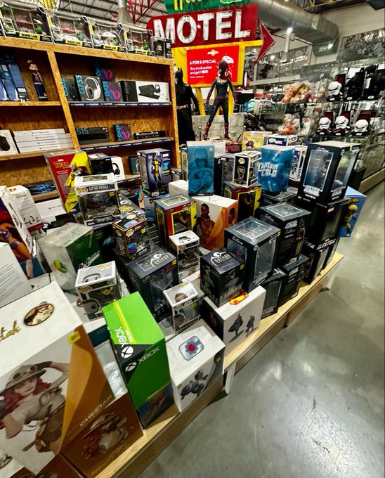 A store display showcases a variety of Funko Pop collectible boxes stacked on a table beneath a red neon 'MOTEL' sign.