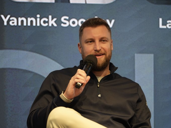 Yannick Socolov, identified by the backdrop, speaks into a microphone at what appears to be a panel discussion, consistent with the accompanying text about his insights on tokenizing real-world assets and the need for traditional credit underwriting.