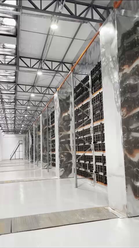 The image shows a large warehouse with rows of shelves filled with black boxes. The warehouse appears to be used for storing goods, possibly related to Bitcoin mining or digital currency. The text in the image suggests that this warehouse is located in Paraguay, specifically in Iguazú, and it houses a Bitcoin mining farm operated by HIVEDigitalTech. This facility has the capacity to power 200 MW using hydroelectricity from Itaipú's dam.
