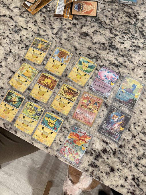 A collection of Pokémon trading cards, including multiple Pikachu cards, Eevee, and other holographic cards spread across a granite countertop.