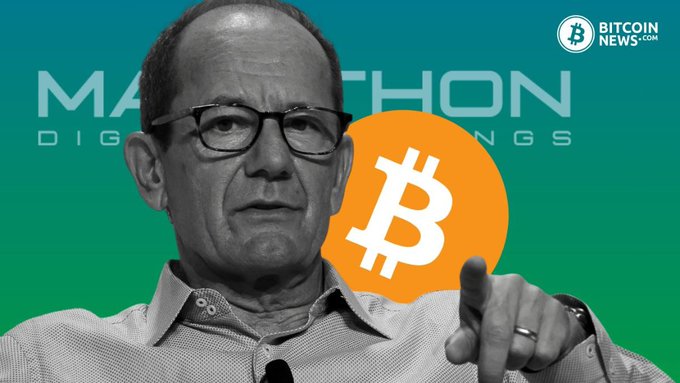 An older man wearing glasses and a button-up shirt points his finger upward against a teal background featuring the "MARA Holdings" logo, an orange Bitcoin symbol, and a "BitcoinNews.com" watermark in the top right corner, visually representing the company's reported Q2 net loss of $611M and a 29% year-over-year decline in its Bitcoin holdings to 35,577 BTC.