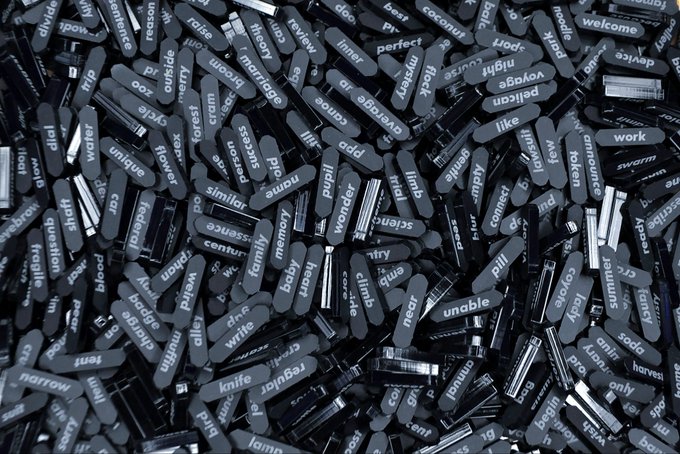 A dense pile of black, rounded rectangular tokens or tiles, each printed with a single white English word such as 'fibre', 'summer', 'belly', 'reason', and 'water'.