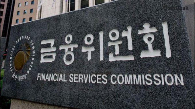 A stone sign displays "금융위원회" (Financial Services Commission) in Korean alongside its English translation and circular emblem. The image relates to the post by showing the headquarters sign of South Korea's Financial Services Commission, the regulatory body working to consolidate multiple digital asset bills into a unified framework.