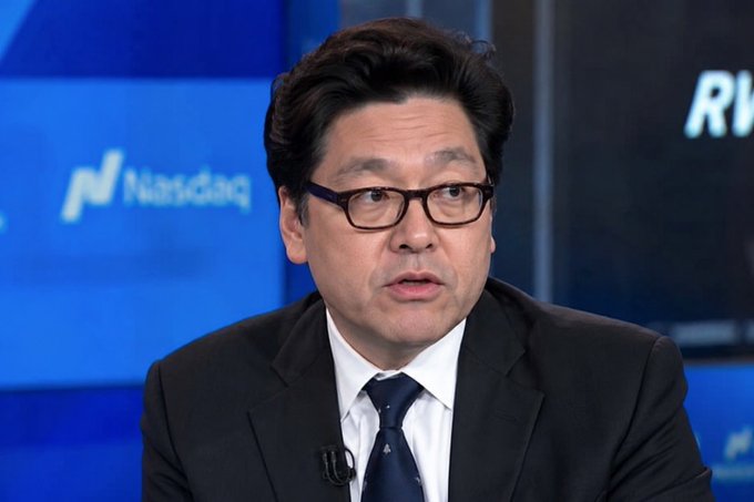 The image shows a man wearing glasses, sitting at a desk with his hands behind his back, appearing to be giving a speech or presentation. The background features a blue screen displaying the words "Nasdaq" and "RV". The man is talking about something related to Ethereum, possibly discussing its supply or market trends.