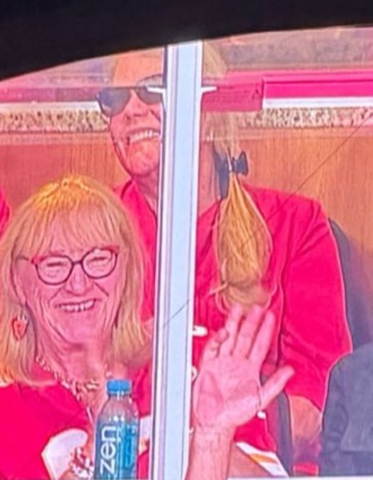 Two women wearing red shirts smile and wave at the camera, with one holding a bottle of Ozarka water, suggesting they are enthusiastically participating in an event—likely a coordinated group activity that prompted the caption "wait andrea fully in red, this is serious."