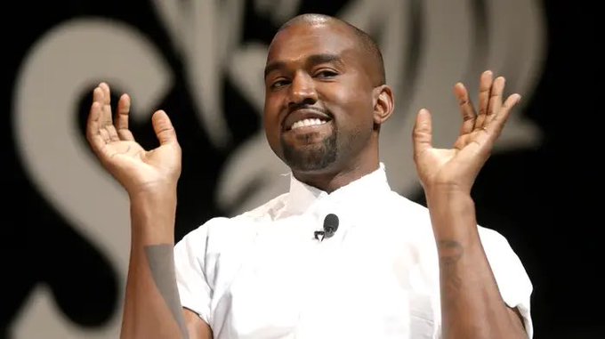 A man with a shaved head and goatee, wearing a white shirt, raises both hands with palms open while smiling, with a blurred logo featuring the letters "SV" visible in the background. The image humorously illustrates the post's confident "not financial advice" bullish market sentiment, evoking the meme-like enthusiasm often associated with celebrity-driven crypto commentary.