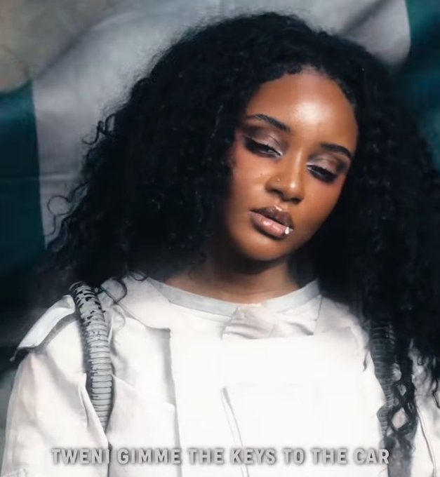A woman with long curly hair and a white jacket looks down with a serene expression, accompanied by the text "TWENI GIMME THE KEYS TO THE CAR." The image appears to be a music-related visual promoting an artist, loosely tying to the weekend mood and motivational "lock in" theme of the post.