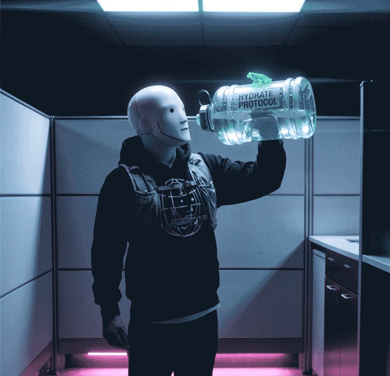 In the image, a person wearing a mask is holding up a water bottle with both hands while standing inside an office cubicle or similar setting. There are also pink lights visible in the background that illuminate the scene. The caption "Remember to stay hydrated" suggests that staying hydrated is important for maintaining good health and well-being.