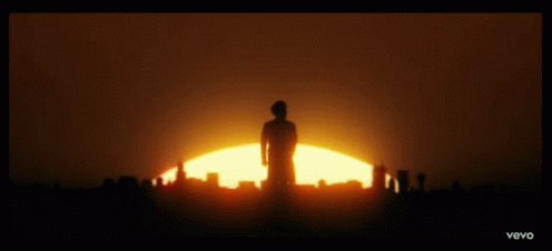 The image features a silhouette of a person standing against an orange sky at sunset. The sun appears to be setting, casting a warm glow over the scene. The person's silhouette stands out prominently against the vibrant colors of the sky.