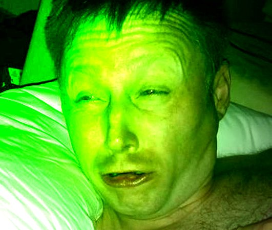 A close-up selfie of a man with short hair, bathed in an intense green light, lying against a pillow, with the caption "$Link $11" suggesting a humorous or lighthearted reference to a cryptocurrency or meme coin.