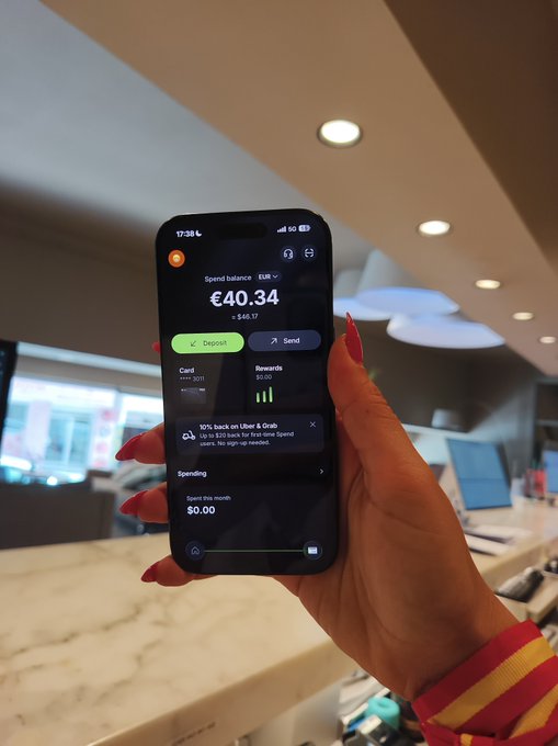 A hand holding a smartphone displaying a crypto wallet app with a EUR spend balance of €40.34 ($46.17), featuring Deposit/Send buttons and a 10% back offer on Uber and Grab.