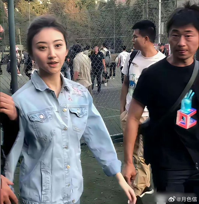 A woman in a light blue denim shirt walks outdoors holding hands with a man in a black t-shirt, with a watermark '@月色信' visible.
