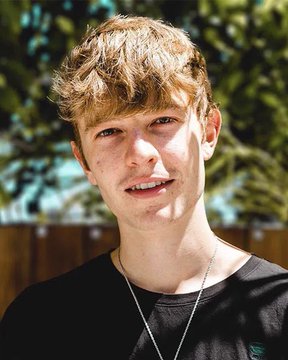 A young man with curly reddish-brown hair, wearing a black shirt and silver chain, stands outdoors with a wooden fence and greenery in the background. The post references FaZe Blaze announcing he has over $250K in his account after joining the PumpFun ecosystem, with the majority attributed to a large token purchase sent to him.
