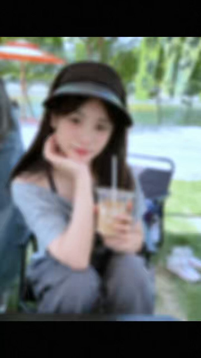The image features a girl sitting outdoors, holding a drink with a straw in her hand. She has a hat on her head and appears to be posing for a photo. The background of the picture shows an outdoor setting with chairs and umbrellas visible. The caption at the bottom of the image reads "我就说一件事： 万无线线猜猜是谁？ FDV 才8000万。".