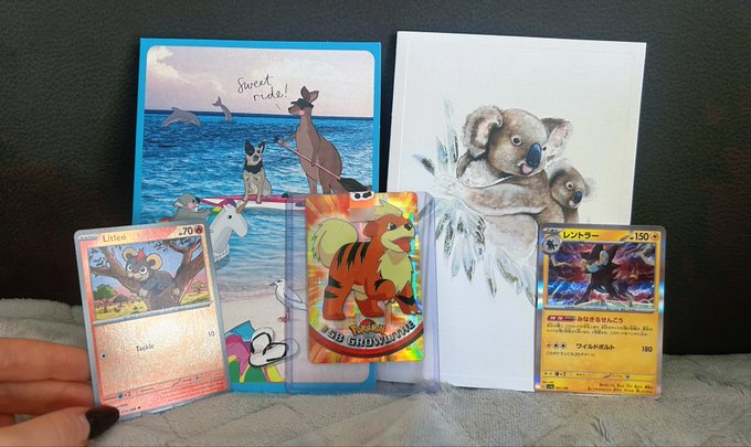 A collection of Pokemon trading cards (Littee, a Growlithe promo card, and a Japanese Blastoise) displayed alongside artwork cards featuring dogs by the sea and a koala with its baby.