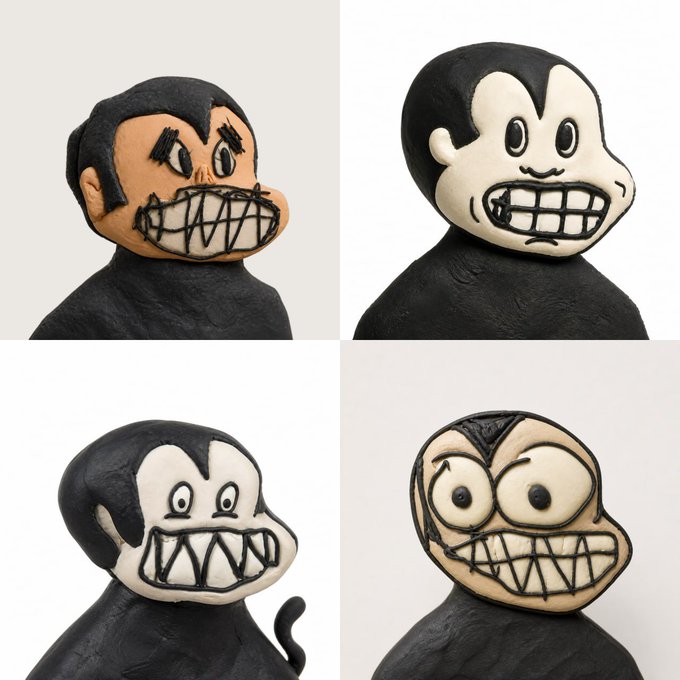 Four clay sculpted figures feature black bodies with white and tan faces displaying exaggerated, grimacing toothy grins.