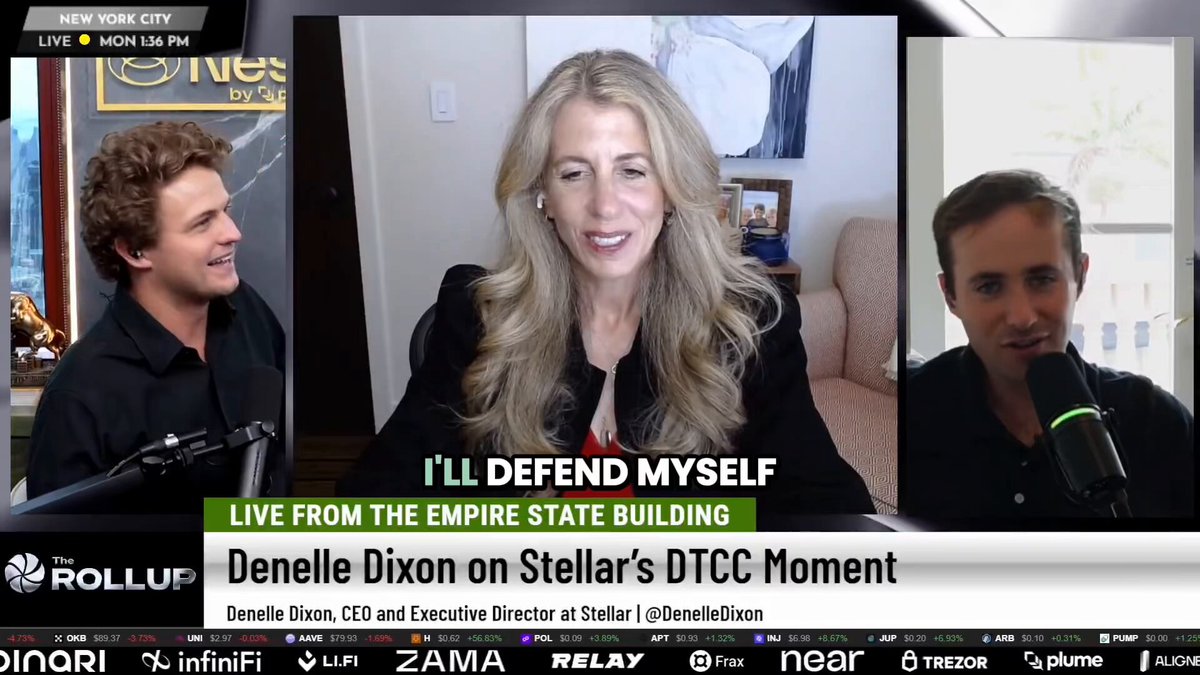 The image shows a television screen displaying three people, with two men and a woman sitting behind them. The women has blonde hair and is wearing a black blazer. They are all smiling at the camera as they appear to be having an interview or participating in a panel discussion on a topic related to the Empire State Building.