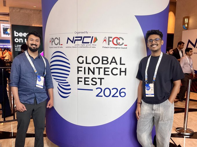 Two smiling men wearing lanyards stand on either side of a banner reading "GLOBAL FINTECH FEST 2026" organized by APCI, NPCII, and AFCC.