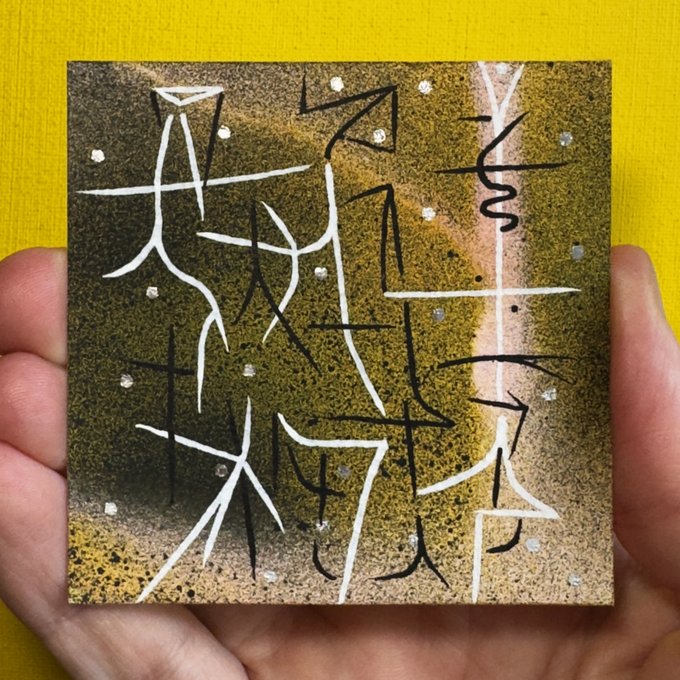 The image shows a hand holding up a small square art piece, which appears to be a painting of Chinese characters. The artwork features black and white lines that create an abstract design with various shapes and symbols. The background color of the painting is yellow, providing contrast to the dark tones of the artwork. The post in question seems to be about collecting or trading on a coin called @zora zora.co/coin/base:0x93, which could potentially be related to the art piece being sold or exhibited.