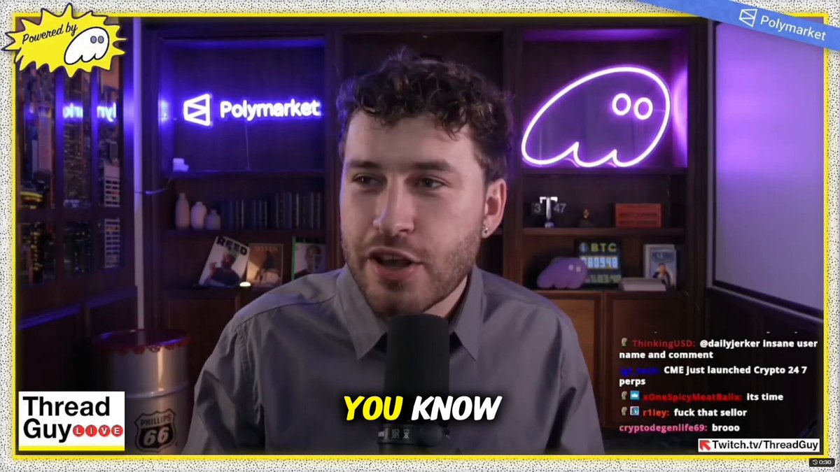 The image shows a man wearing a gray shirt, tie, and glasses talking into a microphone while standing in front of a bookshelf filled with various items such as books and knick-knacks. The background features a purple neon sign that reads "Polymarket" along with an image of a face or cartoon character resembling a ghost.