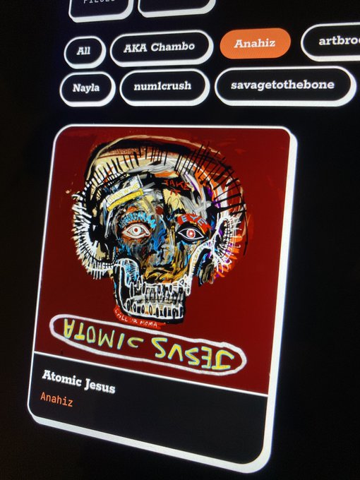 A digital display showing a card with the text 'JESUS WITH MOHA' and 'Atomic Jesus' by artist Anahiz, featuring a colorful illustrated skull artwork, with other usernames visible as filter tabs.