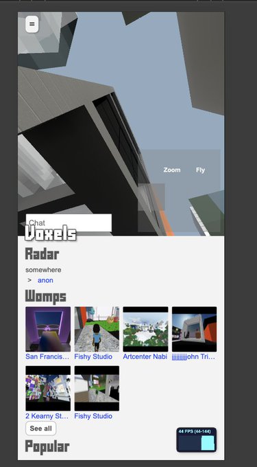 A mobile screenshot of what appears to be a virtual world or gaming app called 'Voxels,' showing a 3D environment with a chat window and sections for 'Radar,' 'Womps' (featuring locations like San Francisco, Fishy Studio, ArcCenter Nabil), and 'Popular' content.
