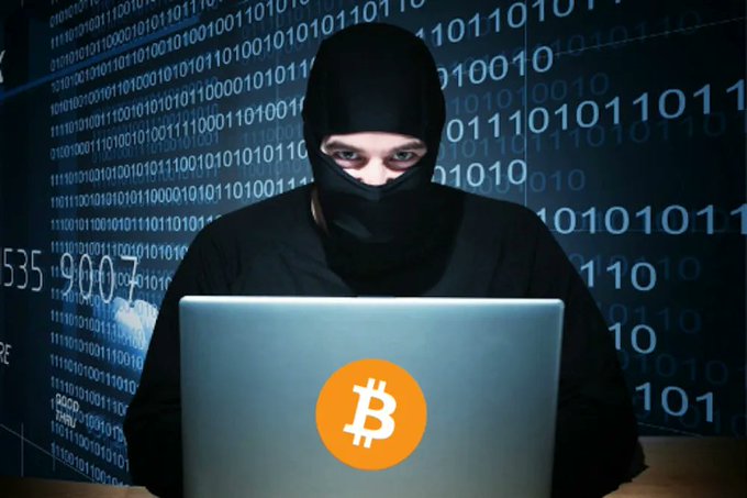 A masked figure sits before a laptop displaying the Bitcoin logo ($BTC) and a backdrop of binary code, illustrating the recent alleged thefts of cryptocurrency by government agents.