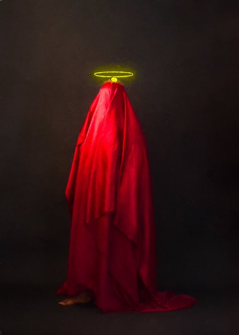 A figure draped in flowing red fabric stands against a dark background, with a glowing yellow halo hovering above their concealed head.