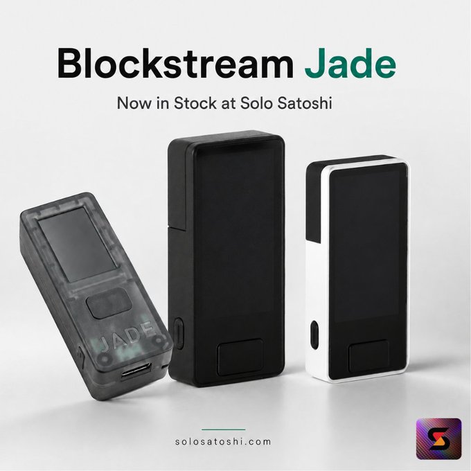 A promotional advertisement for Blockstream Jade hardware wallets, displaying three devices (translucent, black, and white) with text reading 'Blockstream Jade - Now in Stock at Solo Satoshi' and the solosatoshi.com website.