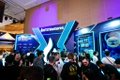 A crowd gathers at HTX's vibrant blue-lit booth during TOKEN2049, where attendees can be seen networking in the event space. The image captures the busy atmosphere of the conference, complementing the post's description of HTX's eye-catching tote bags spreading among participants at the venue.