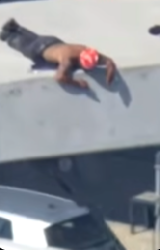 A blurry image of a person's hand resting on a metal surface, possibly part of a climbing obstacle or structure.