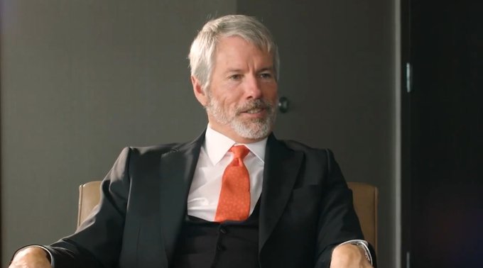 urn of water on a table, with a man in a black suit and red tie seated at the table, suggesting a formal or professional setting.