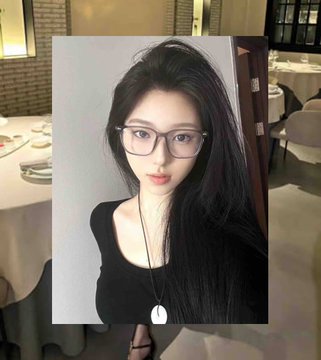 A young woman with long black hair and black glasses wearing a black top and a white pendant necklace, posed indoors.
