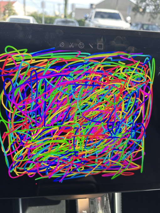 A tablet or drawing screen displays a chaotic, colorful digital scribble filling the entire frame, with a parking lot visible in the background.