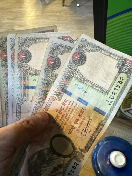 1,000 Iraqi Dinar banknotes fanned out in a person's hand. The bills feature ornate designs with red seals and Arabic text, including a serial number EL 021432 and the denomination 1000.