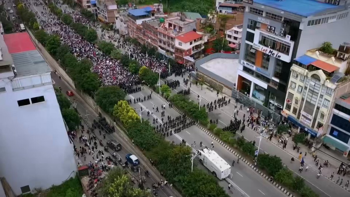The image shows an aerial view of a busy city street with numerous people walking down the road, surrounded by tall buildings. The crowd appears to be gathered for a special event or celebration, possibly a national holiday or a significant occasion. There are also several cars parked along the street and a truck in the foreground. The post about Janamat seems to be related to this gathering, as it mentions that there have been 5+ campaigns launched on social media since then, with 1M Nepalis onboarded onto @solana through Janamat.