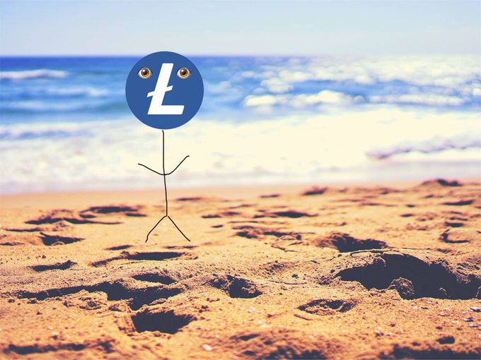 A stick figure with a blue Litecoin (Ł) coin for a head stands on a sandy beach with the ocean in the background. The image playfully represents "Lester," Litecoin's mascot, as referenced in the post.