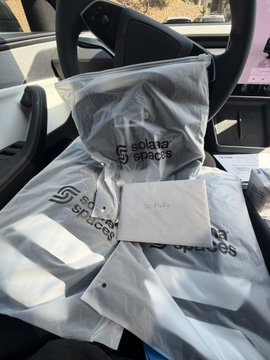 Plastic bags labeled 'Solater Spaces' rest on the passenger seat of a car, with a small handwritten note tucked among them.