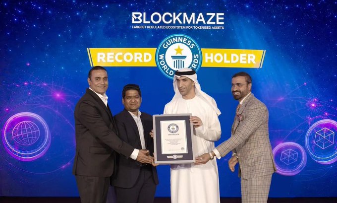 Four men stand on stage holding a framed Guinness World Records certificate, with the backdrop reading "BLOCKMAZE - LARGEST REGULATED ECOSYSTEM FOR TOKENISED ASSETS" and "RECORD HOLDER" flanking the Guinness World Records logo. The image captures Blockmaze's CEO Natty Virk and team at the Dubai ceremony where the company was officially recognized as a Guinness World Record holder, aligning with the post's emphasis on real-world value and trusted governance in tokenized assets.