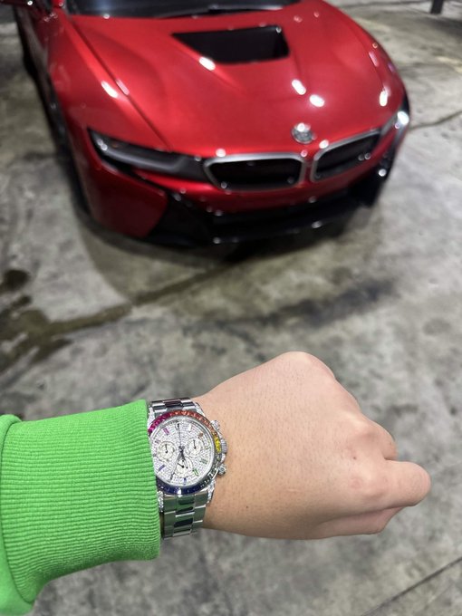 A wrist flexes a Rolex watch in front of a sleek red BMW i8, symbolizing the financial gains from memecoin investments. The luxury pairing of sports car and high-end timepiece visually captures the "Thank you memecoins" sentiment of unexpected crypto wealth.
