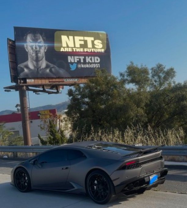 A matte black Lamborghini Huracán is parked beneath a billboard promoting "NFT KID @koklid991" with the bold message "NFTs ARE THE FUTURE," fittingly paired with a bullish crypto/NFT morning post. The luxury supercar and crypto advertisement together convey an aspirational, bullish vibe for the new day.
