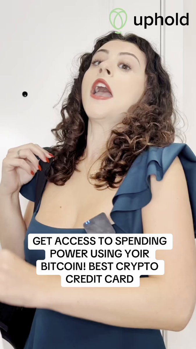 The image features a woman with curly hair wearing a blue dress who appears to be making a funny face or gesture while holding up her credit card. The caption of the image reads, "Stop selling your crypto just to spend! With @UpholdInc’s Exa Credit Card, borrow against your BTC, ETH, XRP & more - Spend anywhere Visa is accepted without touching your stack. No credit check, no annual fees, premium Visa Signature perks". The woman's facial expression and the use of a credit card in the image suggest that she might be discussing or promoting the idea of using credit cards for crypto purchases instead of traditional banking methods.