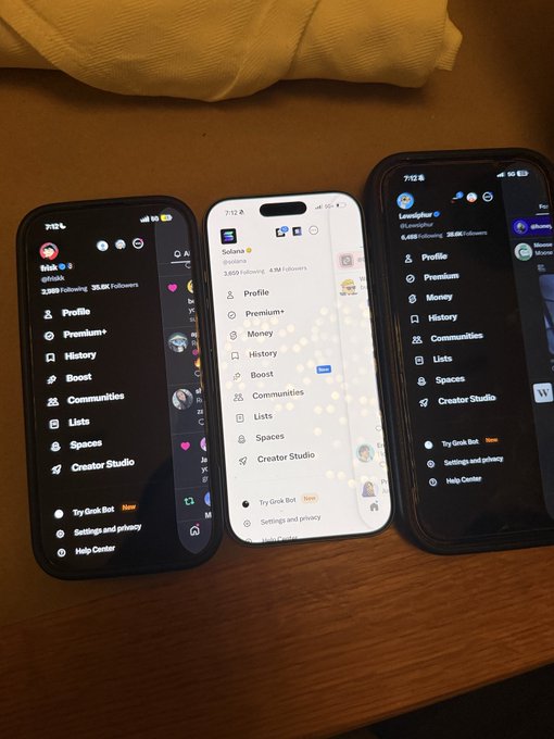 Three smartphones are laid out on a wooden surface, each displaying Twitter/X profile or menu screens showing options like Profile, Premium, Money, History, Boost, Communities, Lists, Spaces, and Creator Studio.
