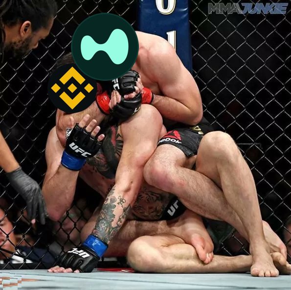 An MMA fight scene in a UFC cage shows one fighter on top of another on the ground, with crypto logos (SUI and BNB) overlaid on their heads and "MMAJUNKIE" watermark visible.