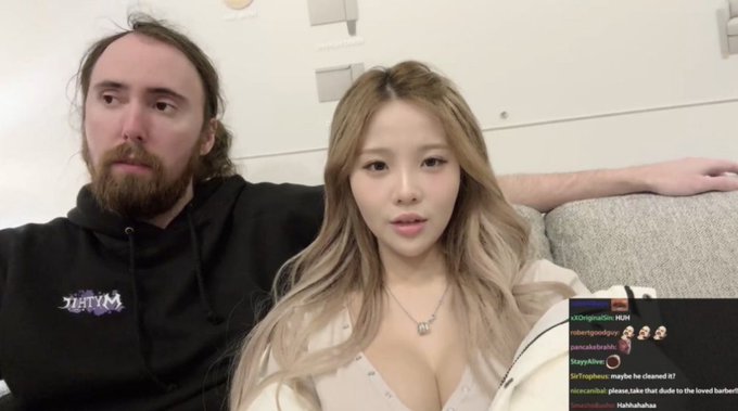 A screenshot from a livestream showing a man with long hair and a bearded man sitting on a couch, with a chat overlay visible in the bottom right corner.